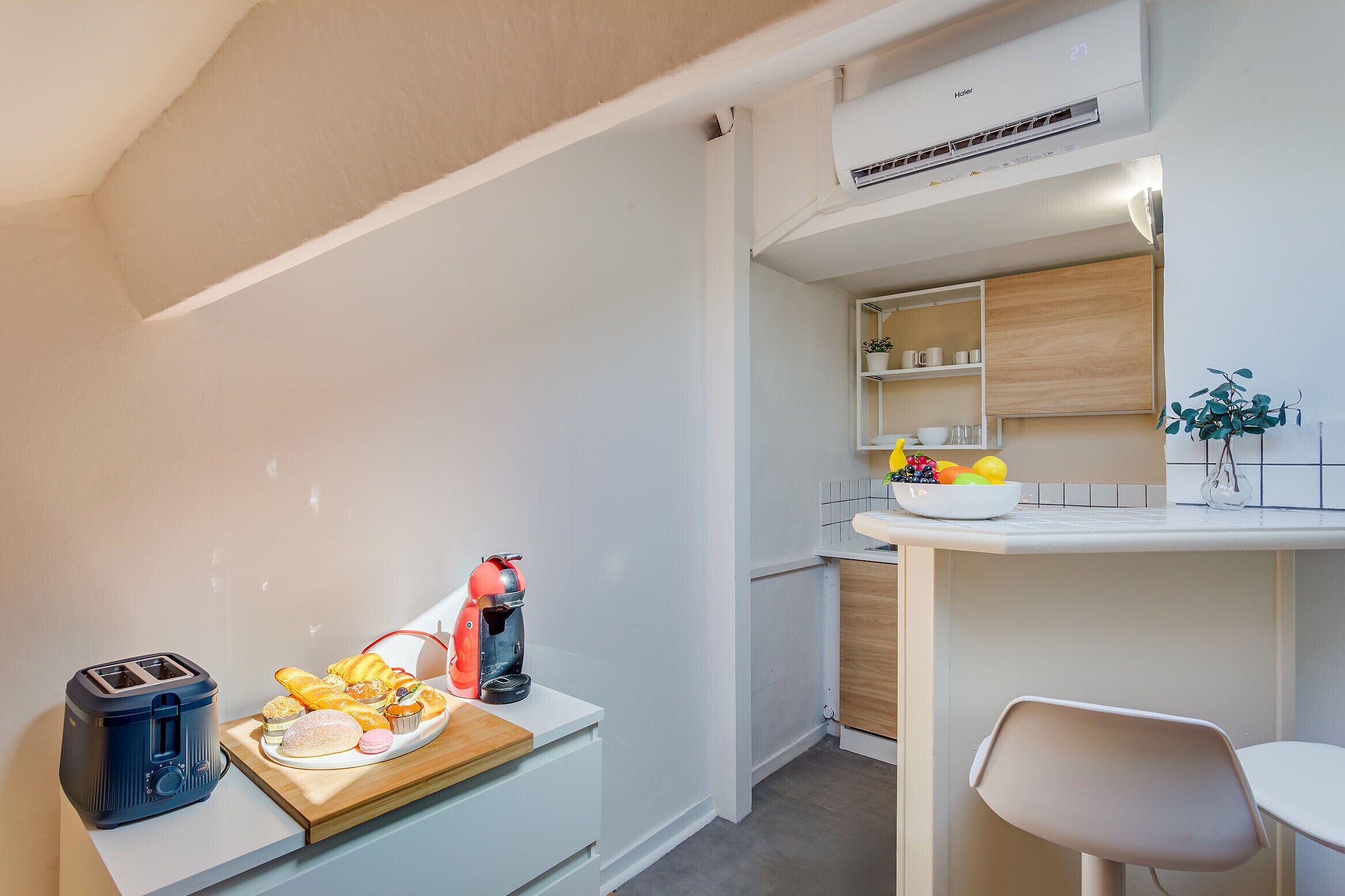 Una kitchenette con una tostadora, un hervidor y un frutero en la encimera.