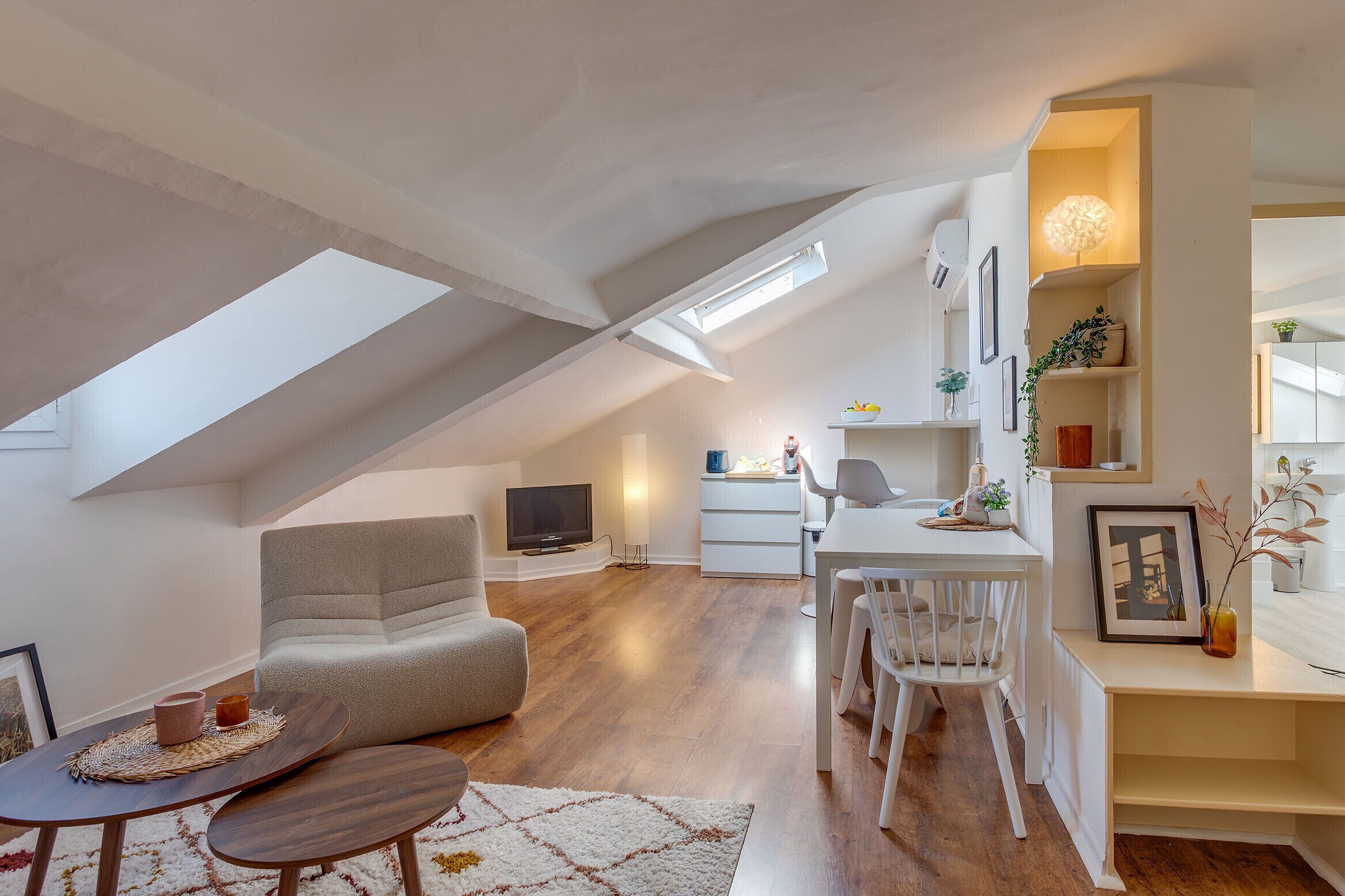 Un appartement moderne de style « loft », comprenant un coin repas, un salon avec canapé, une cuisine et une grande verrière.
