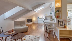 A modern loft apartment with a dining area, a living room with a sofa, a kitchen, and a large skylight. - ATTIC URBAN AP4485 by Riviera Holiday Homes (Niza)