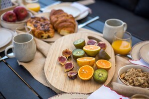 A breakfast setting with fruits, pastries, and beverages on a wooden table.
