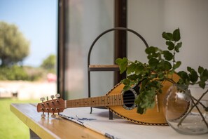 A guitar on a wooden surface with a plant in a glass vase.