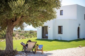 A modern building with a white exterior, a tree in the foreground, and a clear view of the surrounding landscape.
