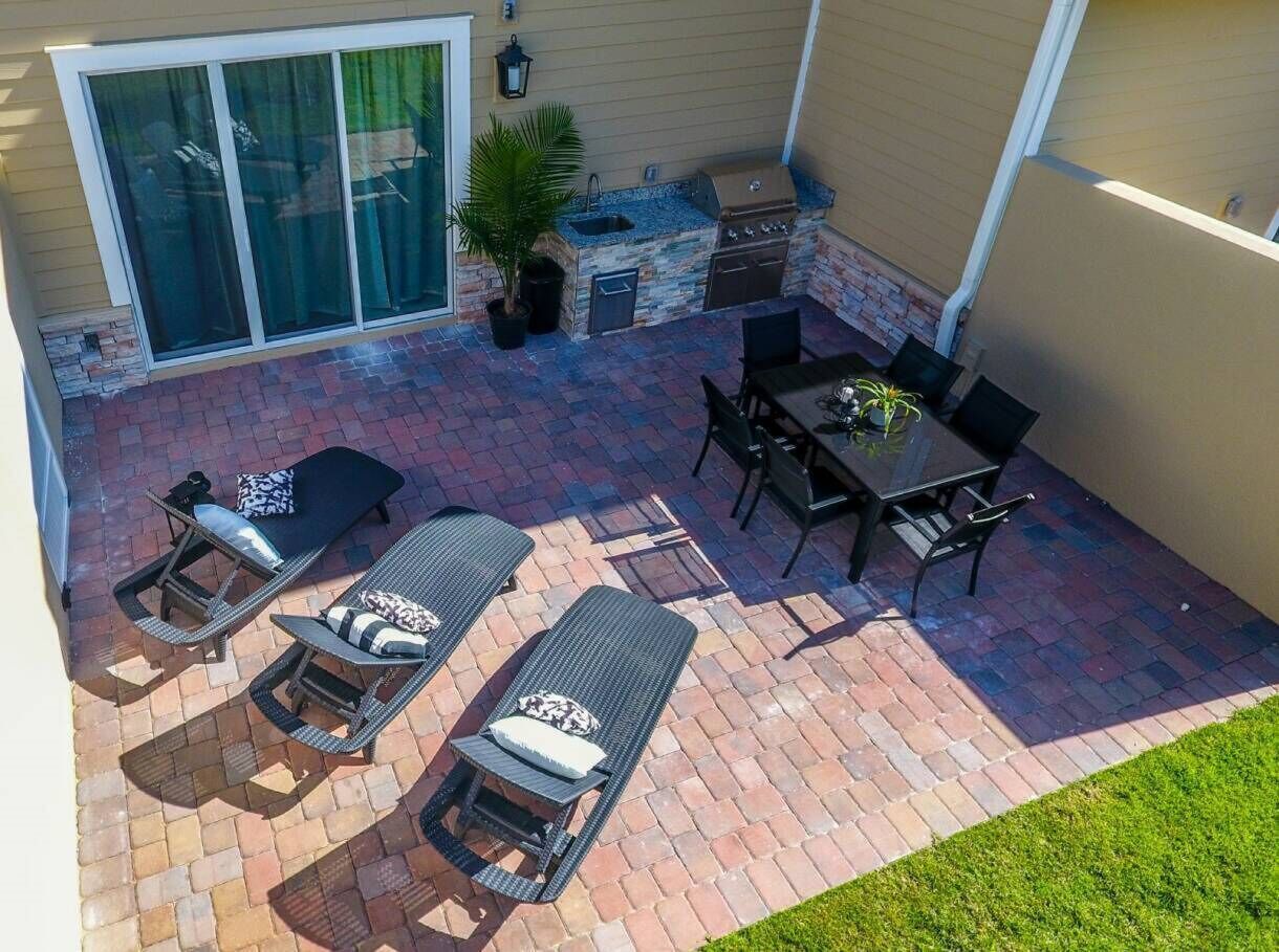 An outdoor patio with a grill, lounge chairs, and a dining table.