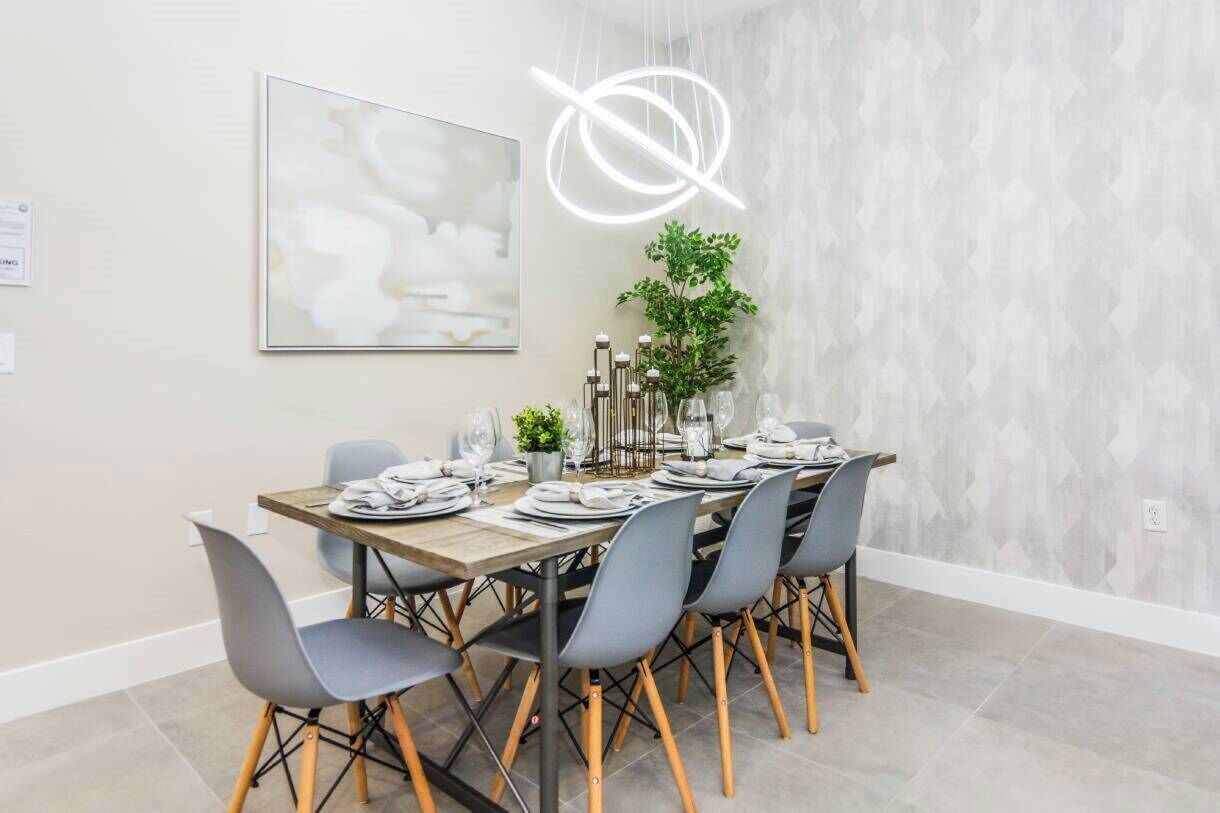 A dining area with a long table set for six, surrounded by modern chairs with wooden legs.