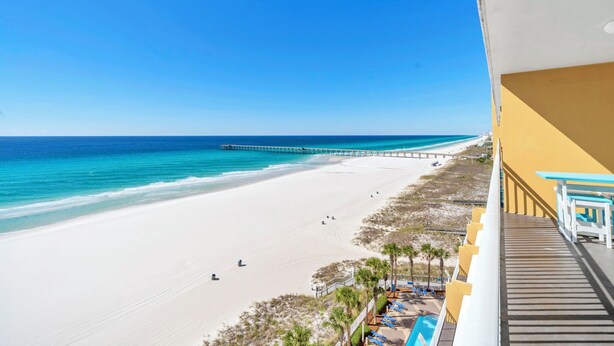 A beach view from a balcony with a pier extending into the ocean, a sandy beach, and a pool area with lounge chairs. - ⭐Beach Front | GULF VIEWS | HUGE Balcony | Pool | Sterling Reef 501⭐ (Panama City Beach)