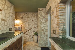 A stone-walled hallway with a tiled floor, a wooden door, and a potted plant. - Treehouse - The Nest (Christiansted)