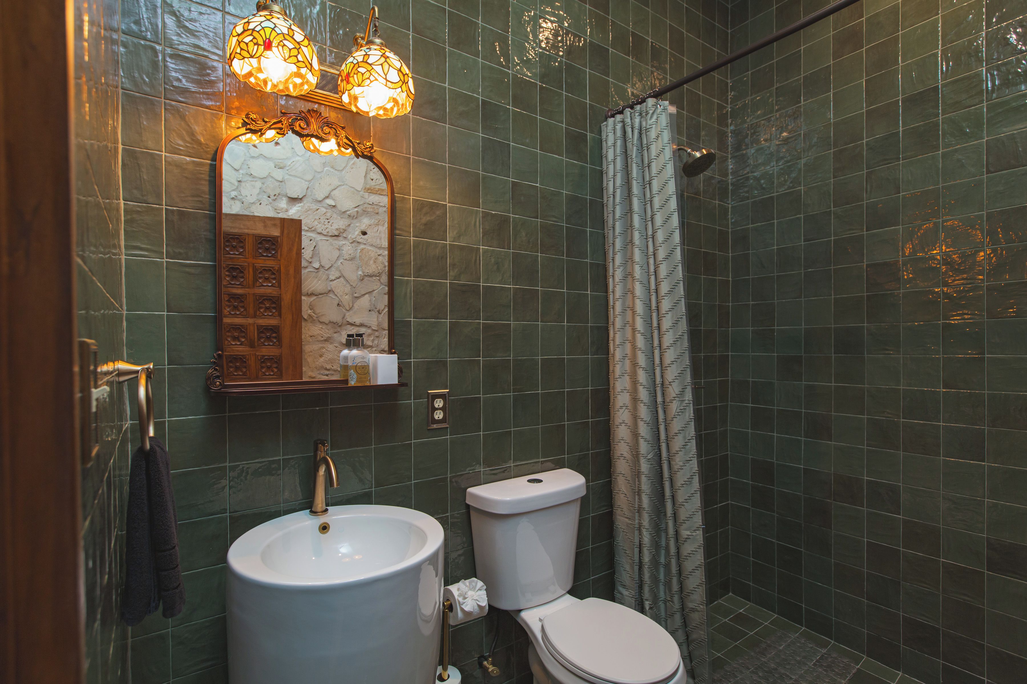 Baño con lavamanos, inodoro y cortina de ducha.