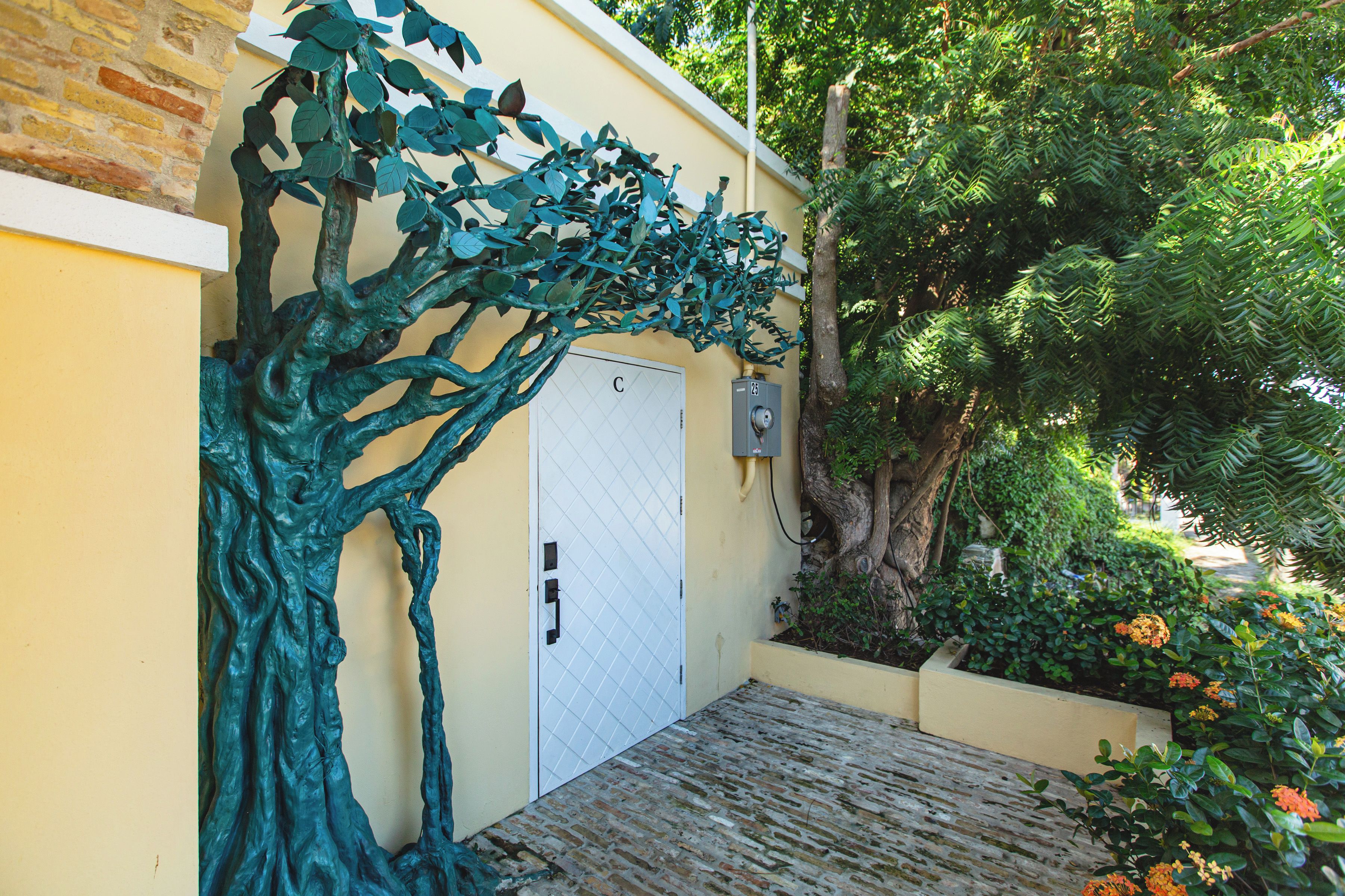 A building with a white door, a metal gate, and a tree sculpture.