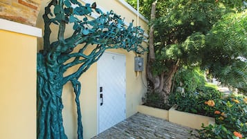 A building with a white door, a metal gate, and a tree sculpture.