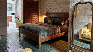 A bedroom with a stone wall, a wooden bed, a mirror, and a view of the outside. - Treehouse - The Observatory (Christiansted)