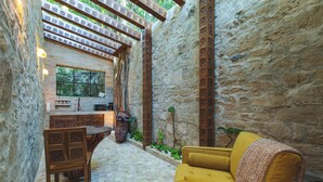 A cozy interior with a stone wall, a wooden table, a yellow sofa, and a window with a view of greenery. - Treehouse - The Observatory (Christiansted)