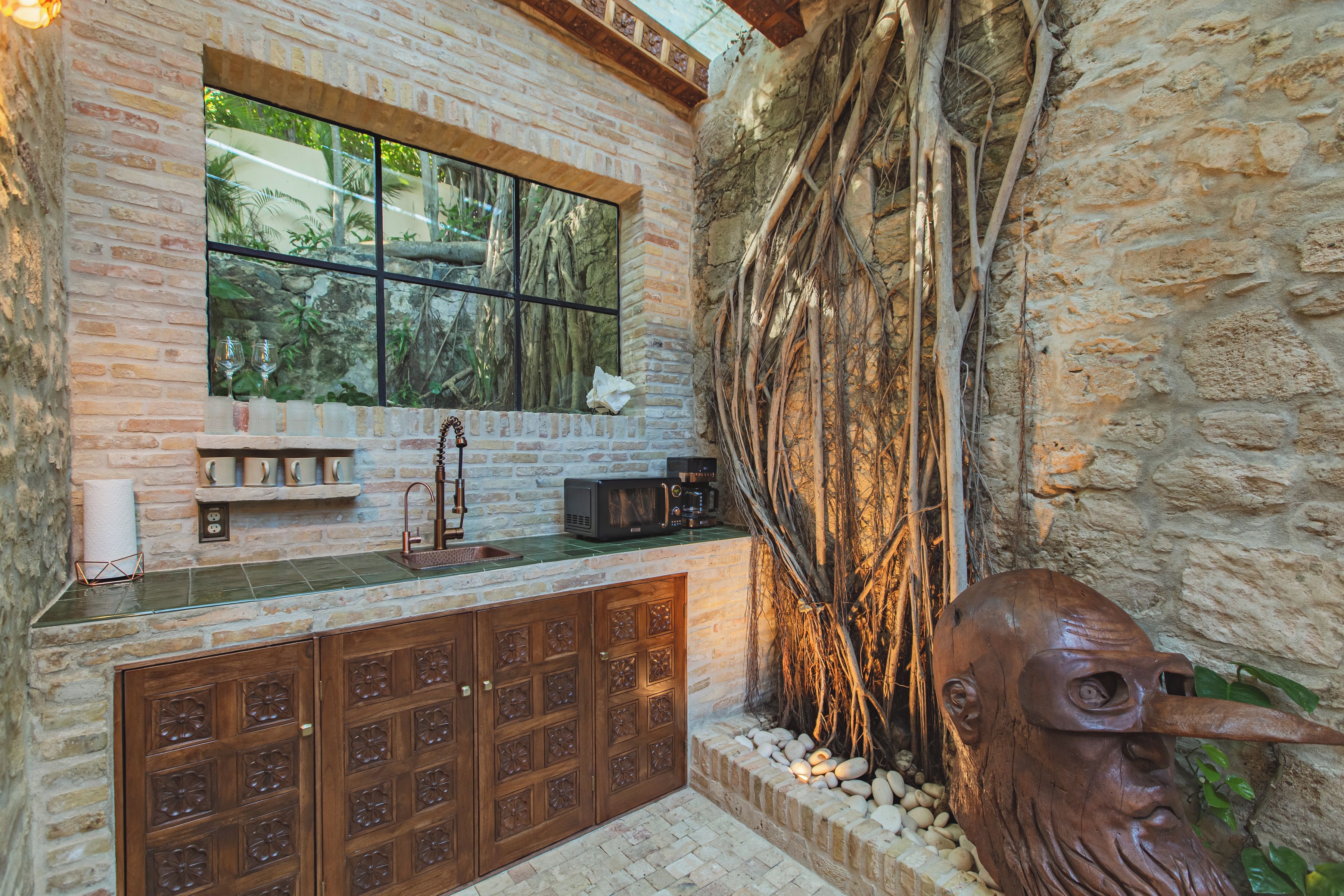 Una cucina con parete in pietra, una finestra e un armadietto in legno dal design originale.