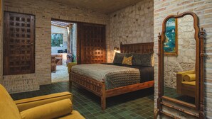 A bedroom with a wooden bed, a mirror, and a view of the outdoors. - Treehouse - The Observatory (Christiansted)