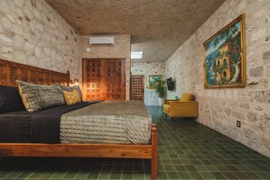 Una habitación con una cama, una puerta de madera, un cuadro y una silla.