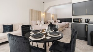 A modern living room with a dining area, a sofa set, and a kitchen area with a microwave and kettle. - Bold St ApartHotel | Book Individually or Book 8! (Liverpool)
