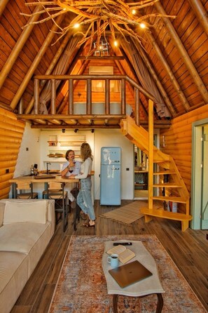 A cozy log cabin interior with a dining area, kitchen, and a loft bedroom. - Rast Sapanca Bungalov (Sapanca)