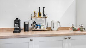 Un plan de travail de cuisine avec une machine à café, un mousseur à lait, un moulin à café, une bouilloire et une tasse à café.