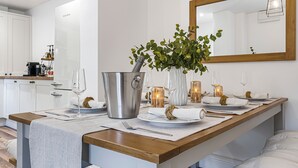 A modern kitchen with white cabinets, a wooden countertop, and a dining area set with plates, glasses, and candles. - BRAND NEW! Renovated luxury 2-bed cottage, parking & garden (Lechlade)