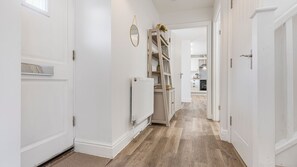 Un couloir aux murs blancs, avec un radiateur et un plancher en bois.