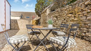 An outdoor seating area with a stone wall, a table, and chairs. - BRAND NEW! Renovated luxury 2-bed cottage, parking & garden (Lechlade)