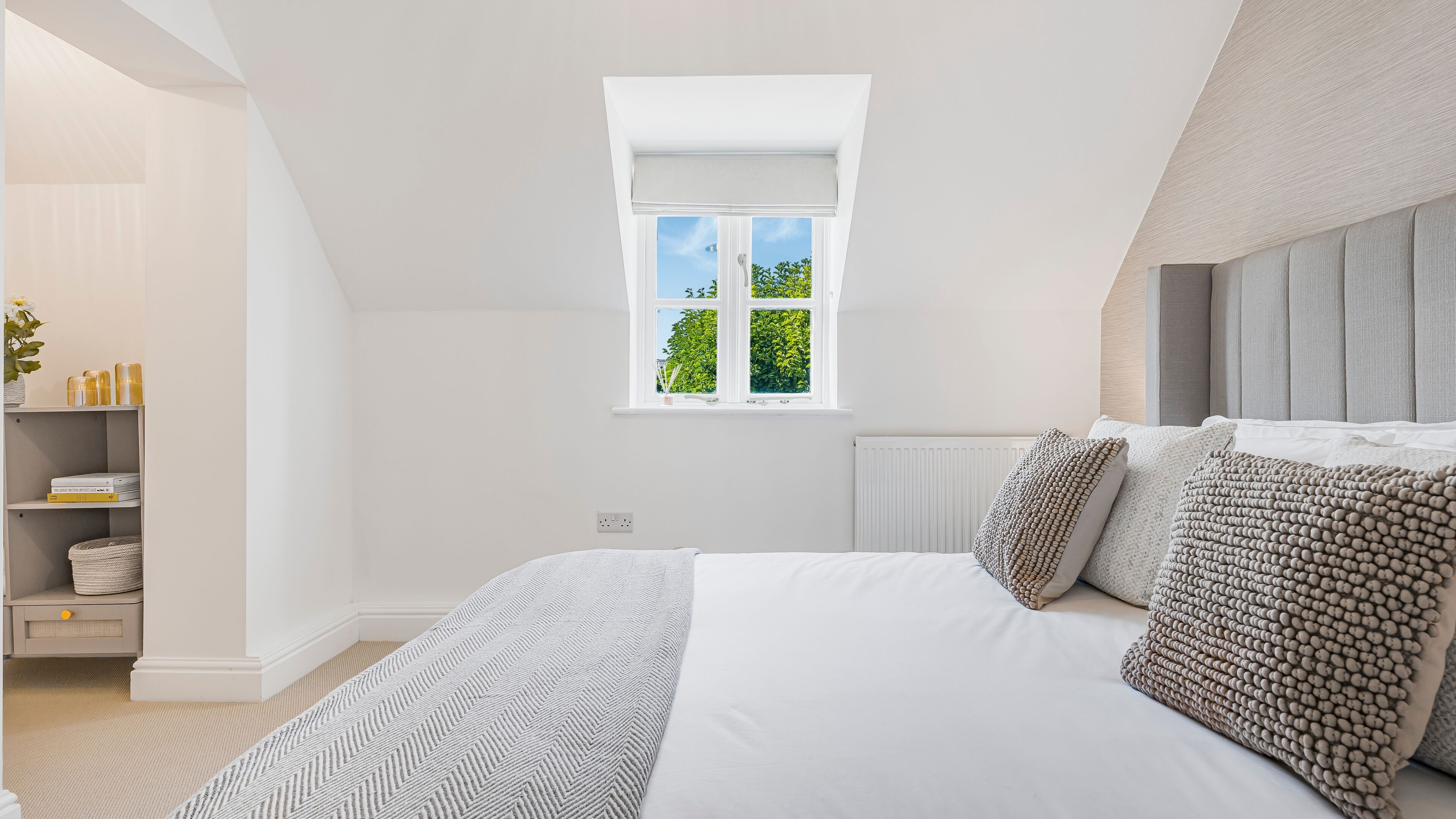 Une chambre avec un grand lit, une fenêtre donnant sur la verdure, une armoire intégrée et un radiateur.