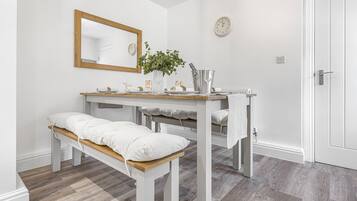 Ein Zimmer mit einer Holzbank, einem Tisch mit Spiegel, einer Uhr und einer Topfpflanze.