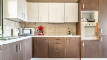 A modern kitchen with wooden cabinets, a microwave, a coffee maker, and an oven.