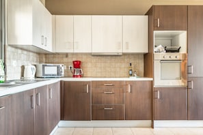 A modern kitchen with wooden cabinets, a microwave, a coffee maker, and an oven.