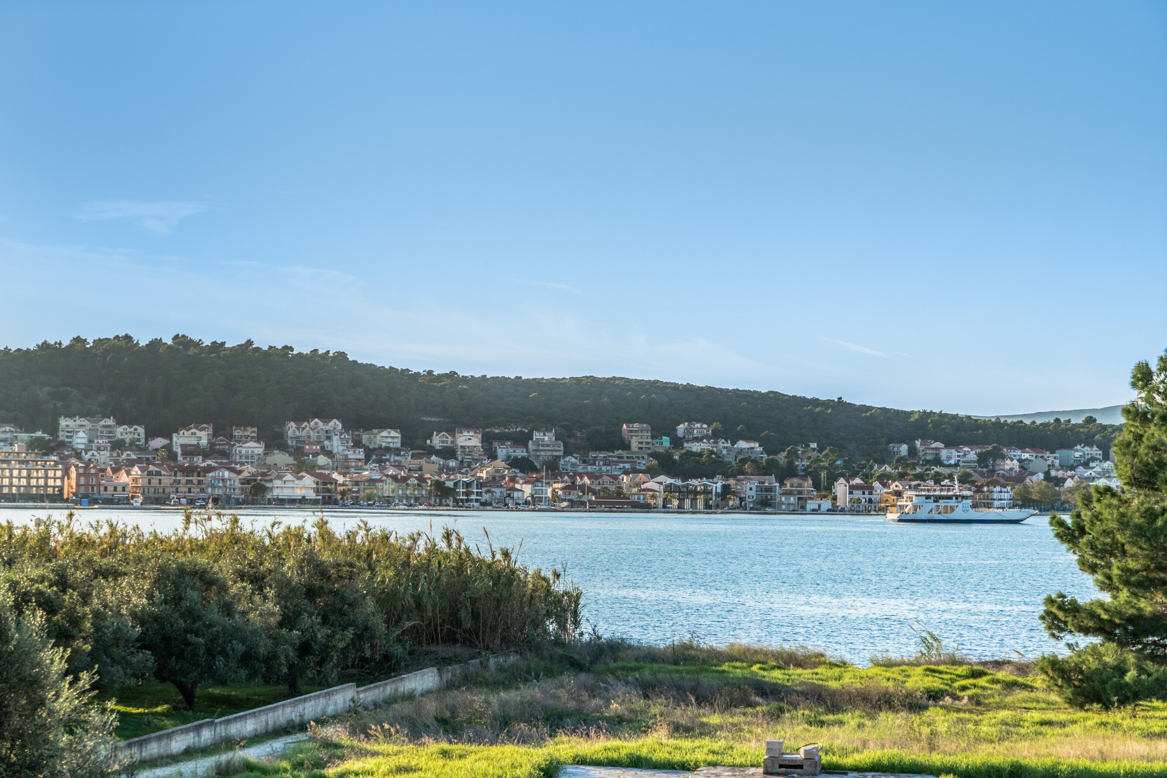 A coastal cityscape with a river, buildings, and a boat.