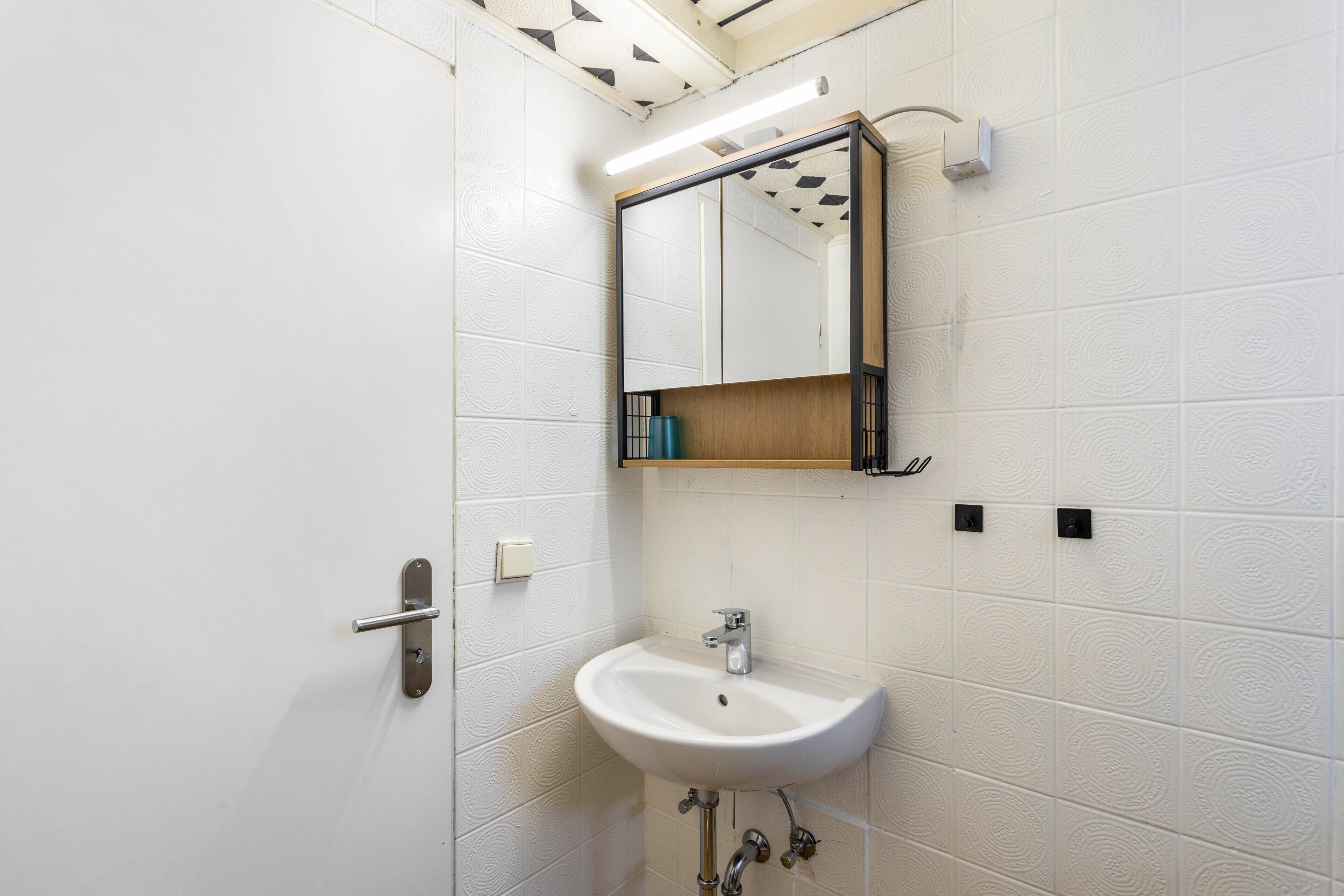 A bathroom with a white sink, a mirror, and a towel rack.