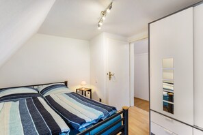 Quarto com cama, mesa de cabeceira e guarda-roupa.