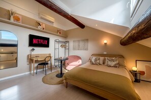 A modern bedroom with a bed, desk, chair, and a wall-mounted TV displaying 'NETFLIX'.