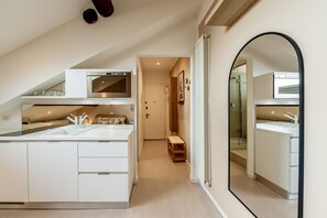 A modern kitchen with white cabinetry, a built-in oven, and a large island with a sink.