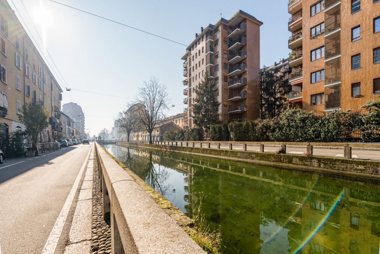 A canal with buildings on one side and a road on the other.