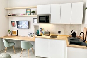 A modern kitchen with white cabinets, a microwave, a sink, and a small dining area with two chairs. - Silent home retreat (5 min Centrale Station) (Milan)