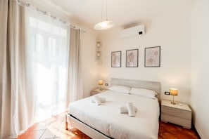 A hotel room with a bed, bedside tables, a window with curtains, and wall art. - Spacious home in Central Station (5 min walk) (Milan)