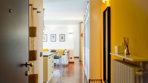 Un pasillo que conduce a una cocina con comedor, que cuenta con un radiador, un banco de madera y cuadros en la pared.