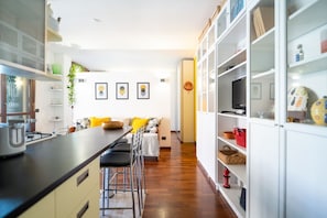 Une cuisine moderne avec un coin repas, des meubles blancs et un téléviseur à écran plat.