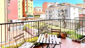 Un balcón con una mesa, sillas y plantas en macetas.