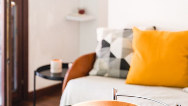 Un dormitorio con cama, una mesita de noche con una vela y una silla.