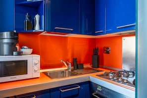 A kitchen with blue cabinets, a microwave, a sink, and a stove.