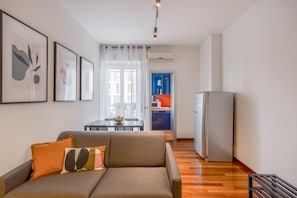 A modern living room with a sofa, a dining table, and a kitchen area in the background.