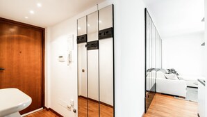 Une pièce moderne avec un plancher en bois, un canapé blanc, un mur blanc et une porte en bois.