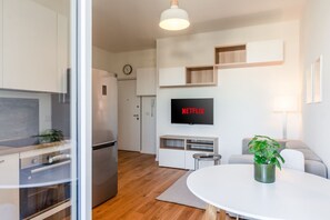 Une cuisine moderne équipée d’un four encastré, d’un réfrigérateur et d’un coin repas avec une table ronde et une plante.