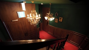A staircase with a wooden handrail, a chandelier, and a red carpeted floor. - kukjejang hotel (Busan)