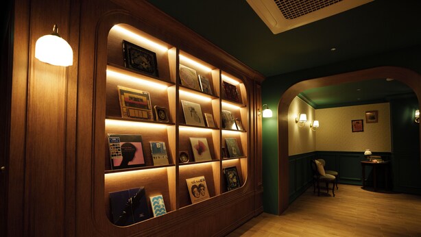 A hallway with a wooden display case containing framed items. There is a chair and a small table in the background. - kukjejang hotel (Busan)