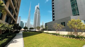 A modern urban landscape with high-rise buildings, a well-maintained grassy area, and a clear sky. - Fabulous Burj Khalifa Views - 5min walk to Dubai Mall (Dubai)