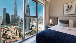 A hotel room with a large window offering a cityscape view, a neatly made bed, and a framed artwork on the wall. - Fabulous Burj Khalifa Views - 5min walk to Dubai Mall (Dubai)