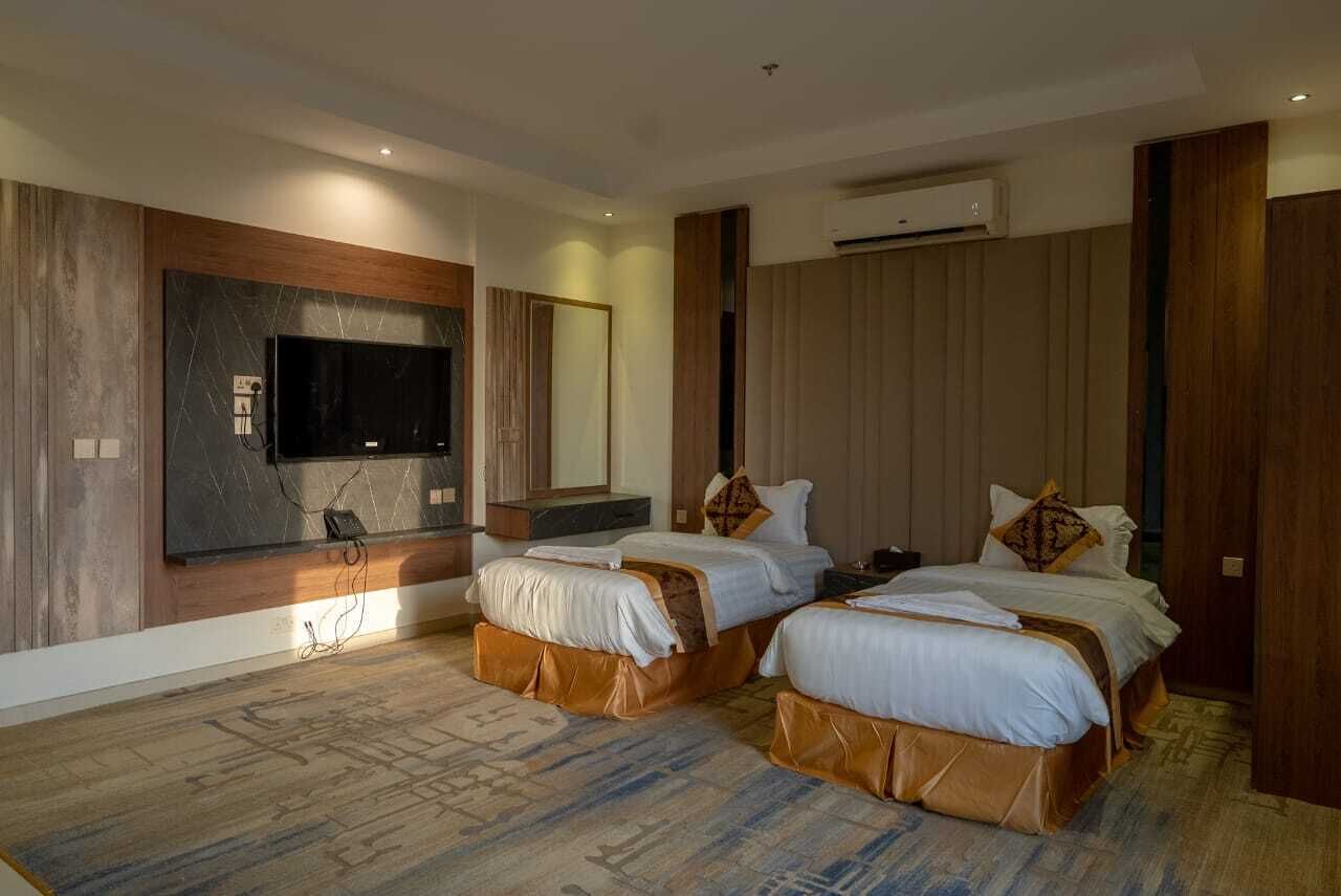 Une chambre d’hôtel avec deux lits, un téléviseur à écran plat fixé au mur et un appareil de climatisation.