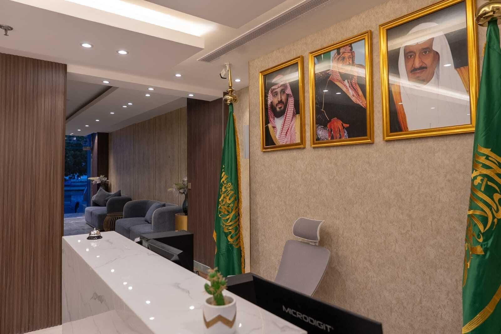 A modern reception area with a marble counter, framed portraits, and a green flag.